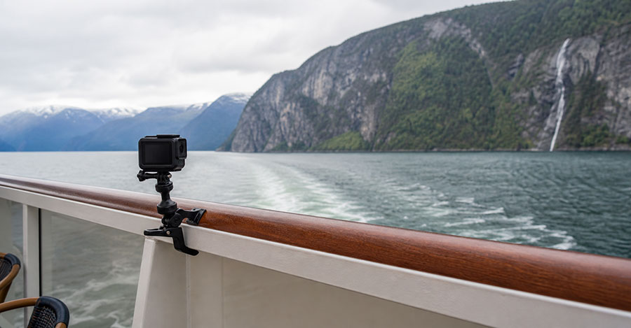 An action camera clamped securely inside a cruise ship balcony as mountains and water pass by.